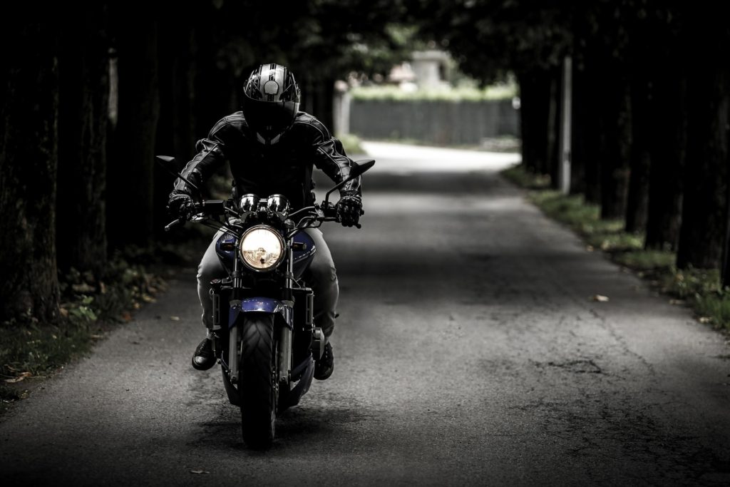 A man driving his blue motorcycle towards the camera for Motorcycle Insurance.