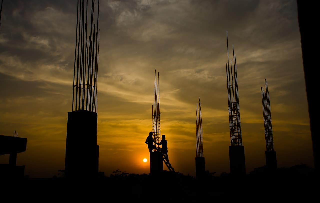 Electricians working at great heights on a tower with sunset in background for Works Comp Insurance.