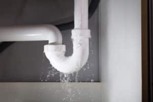 water leaking from a white pipe that a plumber could be liable for without plumbers' insurance