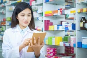 retail pharmacist goes over professional liability insurance in front of shelves of colorful medications