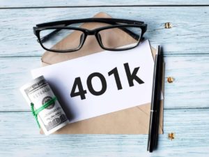 401k written on a piece of paper next to cash, a pen, and sunglasses