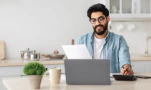 man reviewing his life insurance policy at the counter with his computer