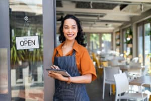 Female startup business owner at cafe entrance using digital tablet