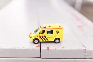 A yellow toy ambulance sits on top of a table.