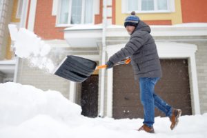 man clearing snow from house covered by disaster coverage