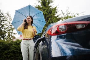 woman standing by car that is covered by personal umbrella insurance