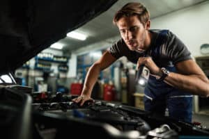 mechanic fixing car part covered with car warranty