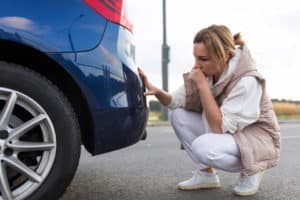 woman looking at car paint damage