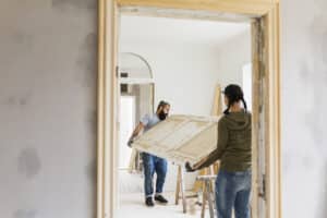 couple carrying door during home renovation