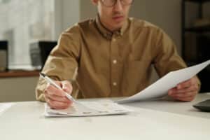 man filling out stack of paperwork