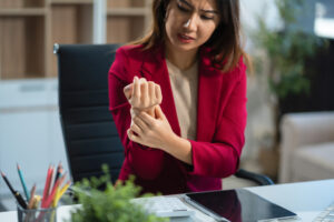 Woman in office holding a hurt wrist