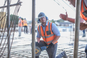 Site manager explaining workers' comp insurance costs to a construction team member