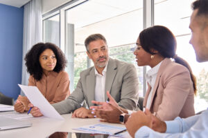 Group of four adults in business clothes sit at a table