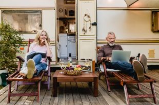 Portrait of senior married caucasian couple having rest on the deck chairs with food and wine just against their caravan home Motorhome & RV Insurance Coverage