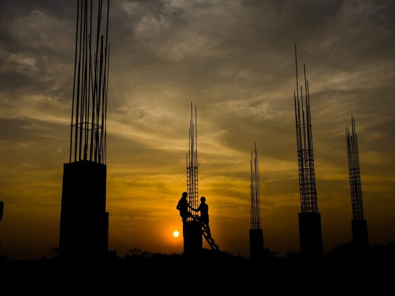 Electricians working at great heights on a tower with sunset in background for Works Comp Insurance.
